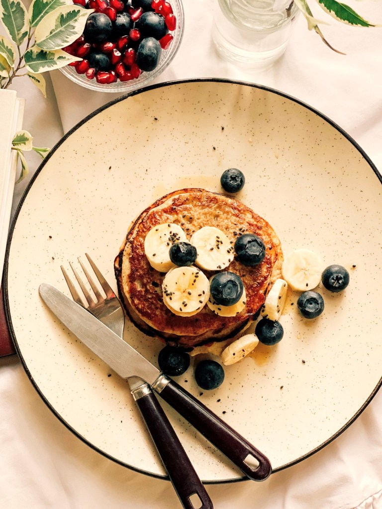 Healthy banana oat pancakes topped with banana slices, fresh blueberries and chia seeds